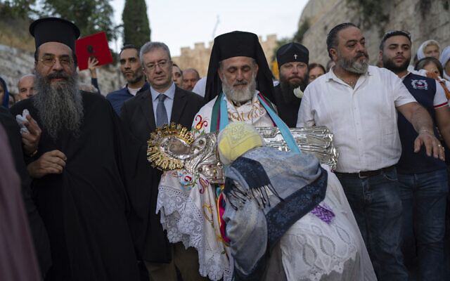 An Orthodox priest followed by pilgrims carries an icon of the Virgin Mary during a procession to bring the icon to the tomb where it is believed she is buried, just outside Jerusalem's Old City, early Friday, Aug. 25, 2023. (AP/Ohad Zwigenberg)