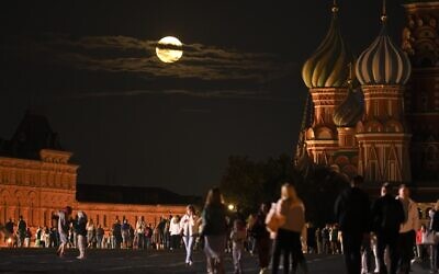 The August Super Blue Moon sets behind a historical building and the St. Basil's Cathedral, right, as people walk in Red Square in Moscow, Russia, August 30, 2023. (Alexander Zemlianichenko/AP)