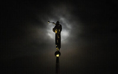 The blue supermoon rises behind a thick layer of clouds near a statue of the angel Moroni perched atop The Church of Jesus Christ of Latter-day Saints, in Kensington, Maryland, August 30, 2023. (Julio Cortez/AP)