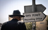 An ultra-Orthodox Jew walks outside the army recruitment office in Jerusalem, August 16, 2023. (Chaim Goldberg/Flash90)