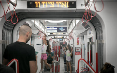 Passengers ride the Tel Aviv light rail on its first day of service, August 18, 2023. (Miriam Alster/Flash90)