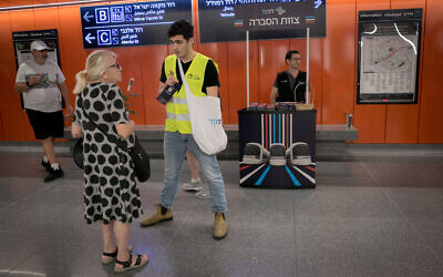 A passenger speaks to staff at a Tel Aviv light rail station on its first day of service, August 18, 2023. (Miriam Alster/Flash90)