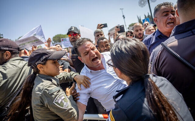 MK Ayman Odeh is pushed by police during a protest against Finance Minister Bezalel Smotrich's decision to freeze funds earmarked for Arab municipalities, outside the Finance Ministry in Jerusalem, on August 13, 2023. (Yonatan Sindel/Flash90) MK Ayman Odeh is pushed by police during a protest against Finance Minister Bezalel Smotrich's decision to freeze funds earmarked for Arab municipalities, outside the Finance Ministry in Jerusalem, on August 13, 2023. (Yonatan Sindel/Flash90)