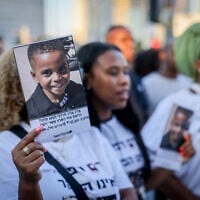 A woman holds up a photo of 4-year-old Rafael Adana, during a protest in Tel Aviv on August 30, 2023, calling for justice after he was killed in a hit-and-run in Netanya in May. (Chaim Goldberg/Flash90)