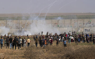 Palestinian protesters run to cover from tear gas during clashes with Israeli troops, along the frontier with Israel, east of Gaza City, Monday, August 21, 2023. (AP Photo/Adel Hana)