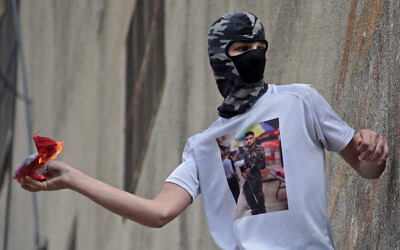 Illustrative: A Palestinian hurls a Molotov cocktail amid clashes with Israeli security forces in the West Bank city of Hebron, October 20, 2022. (MOSAB SHAWER / AFP)