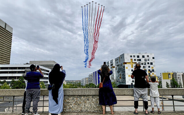 FILE - Residents watch jets from the Patrouille de France flying over Paris suburb Nanterre during the Bastille Day military parade on July 14, 2023 in Nanterre (AP Photo/Youcef Bounab, File) FILE - Residents watch jets from the Patrouille de France flying over Paris suburb Nanterre during the Bastille Day military parade on July 14, 2023 in Nanterre (AP Photo/Youcef Bounab, File)