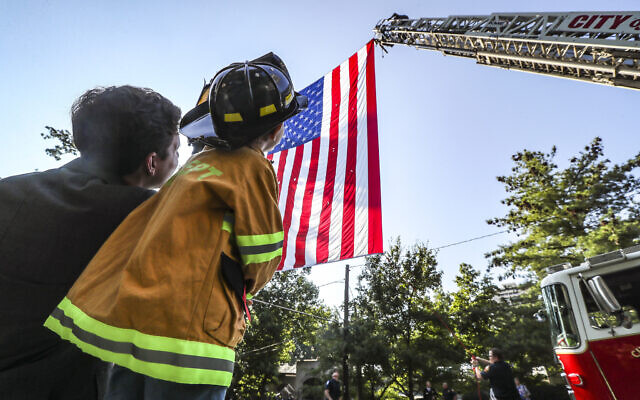 Mark Colker, right, dressed out to see his favorite firefighters alongside his father, Steven Cocker, left, who works in the music department at the Cathedral of Christ the King as they both watched Atlanta firefighters post an American flags between two ladder trucks. Atlanta police and firefighters were in attendance on Monday, Sept. 11, 2023 in Atlanta. The annual Mass honors public safety officials and first responders. City of Atlanta Mayor, Andre Dickens, along with police, fire officials and honor guards participated in the solemn Mass led by Rector, Monsignor Francis G. McNamee. Wreaths were posted in front of the of the church, honoring those who lost their lives on Sept. 11, 2001. (John Spink/Atlanta Journal-Constitution via AP)