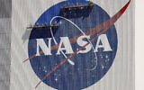 Workers on scaffolding repaint the NASA logo near the top of the Vehicle Assembly Building at the Kennedy Space Center in Cape Canaveral, Florida, May 20, 2020. (AP Photo/John Raoux, File)