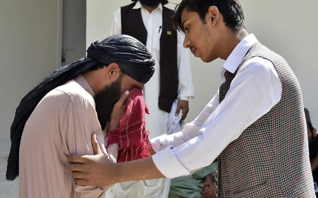 A man comforts another mourning for his relative, who was killed in the bomb explosion, at a hospital, in Quetta, Pakistan, Friday, Sept. 29, 2023. (AP/Arshad Butt)