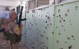 A member of a joint Palestinian security force looks at a wall full of bullet holes inside a school run by the UN agency for Palestinian refugees, UNRWA, in the Palestinian refugee camp of Ein el-Hilweh near the southern port city of Sidon, Lebanon, September 29, 2023. (AP Photo/Mohammed Zaatari)