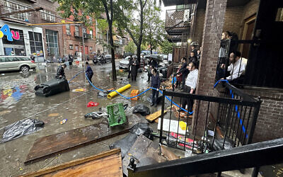Residents watch as workers attempt to clear a drain in flood waters, September 29, 2023, in the Brooklyn borough of New York. (AP Photo/Jake Offenhartz)