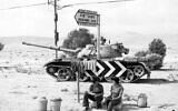 Two Israeli soldiers sit beneath a road sign, with a tank in the background, somewhere in the Sinai Desert, October 8, 1973. (AP Photo/Robert Dear)