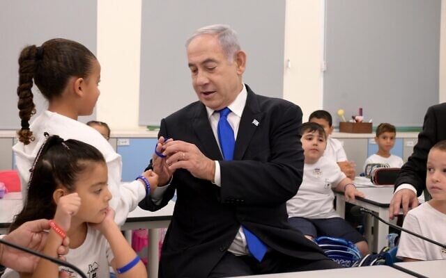 Prime Minister Benjamin Netanyahu looks at a plastic bracelet as he visits first graders in Ma'ale Adumim, September 1, 2023. (Avi Ohayon/GPO) Prime Minister Benjamin Netanyahu looks at a plastic bracelet as he visits first graders in Ma'ale Adumim, September 1, 2023. (Avi Ohayon/GPO)