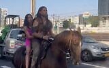 Screen capture from video of Michal Weizman, left, and Roy Oz, riding a horse along the Ayalon Highway in Tel Aviv, September 6, 2023. (X. Used in accordance with Clause 27a of the Copyright Law)