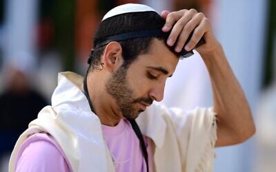 Illustrative: A Jewish man prays with tefillin and prayer shawl at a mass prayer for in Habima Square in Tel Aviv on August 2, 2023. (Tomer Neuberg/Flash90)