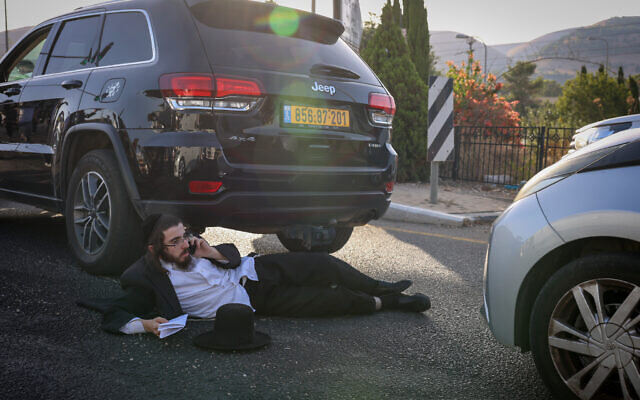 A Haredi man blocks a road in Rosh Pina in protest of the arrest of an ultra-Orthodox military draft dodger, September 13, 2023. (David Cohen/Flash90)
