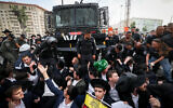 Haredi men block a police vehicle at the entrance to Jerusalem in protest of the arrest of an ultra-Orthodox military draft dodger, September 13, 2023. (Yonatan Sindel/Flash90)