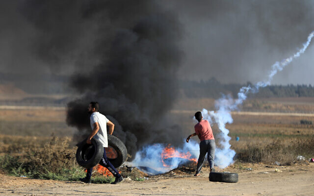 Palestinian rioters carry tires amid clash with Israeli soldiers on the Gaza border, east of Khan Yunis, September 17, 2023. (Yousef Mohammed/Flash90)