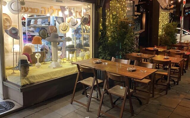 At night, tables from a nearby pub spill out into the sidewalk, against the backdrop of the Dalia's Hats window display. (Courtesy)