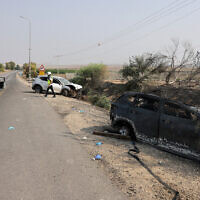A member of Magen David Adom emergency medical services checks cars shot at a day earlier by Gazan terrorists near Sderot on October 8, 2023. (Menahem KAHANA / AFP)