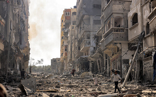 A man carries a propane gas cylinder on his back while walking through debris and destruction littering a street in the Jabalia camp in Gaza City on October 11, 2023 (Photo by MAHMUD HAMS / AFP) A man carries a propane gas cylinder on his back while walking through debris and destruction littering a street in the Jabalia camp in Gaza City on October 11, 2023 (Photo by MAHMUD HAMS / AFP)