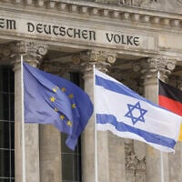 The Israeli flag flutters between the European (L) and the German flag in front of the Reichstag building hosting the Bundestag, the German lower house of Parliament in Berlin, while the German chancellor gave a speech on the Israel-Hamas conflict during a Bundestag session on October 12, 2023. (Odd Andersen/AFP)