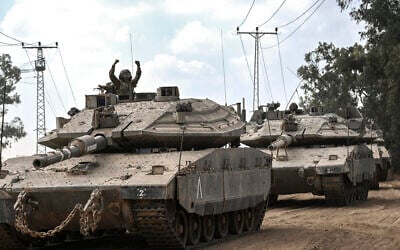 An Israeli soldier gestures from the turret of a Merkava battle tank, as it deploys along the border with the Gaza Strip in southern Israel on October 13, 2023 (Aris MESSINIS / AFP)