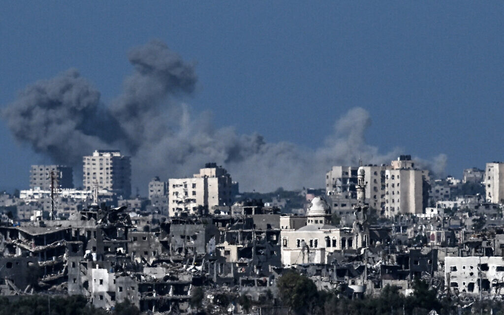 A picture taken from the Israeli side of the border with the Gaza Strip shows smoke rising behind destroyed buildings in the northwestern part of the Palestinian enclave during Israeli strikes on Hamas on October 21, 2023 (Photo by Aris MESSINIS / AFP)