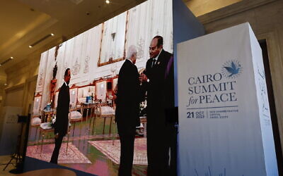 Seen on a large screen, Palestinian Authority President Mahmoud Abbas is greeted by Egyptian President Abdel-Fattah el-Sissi (right) prior to the start of the International 'Summit for Peace,' in the New Administrative Capital (NAC), east of Cairo, on October 21, 2023. (Khaled DESOUKI/ AFP)