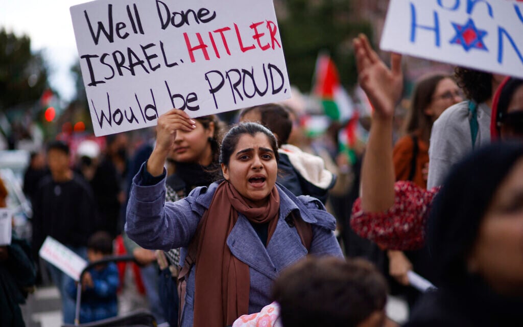 A woman holds a sign reading 'Well Done Israel, Hitler Would Be Proud' as people rally in Brooklyn, New York in support of Palestinians and against Israel in the wake of the October 7 Hamas terror onslaught, October 21, 2023 (KENA BETANCUR / AFP)