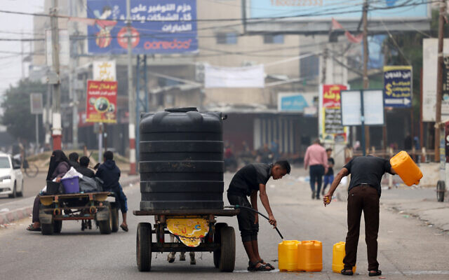 Men fill plastic jerricans with portable water in Rafah, in the southern Gaza Strip on October 23, 2023 (Photo by MOHAMMED ABED / AFP) Men fill plastic jerricans with portable water in Rafah, in the southern Gaza Strip on October 23, 2023 (Photo by MOHAMMED ABED / AFP)