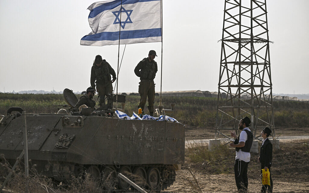 Israeli soldiers on an armored vehicle speak with an ultra Orthodox man as they deploy near Israel's border with the Gaza Strip on October 24, 2023. (Photo by Aris Messinis /AFP)