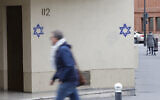 A man walks next to a building the façade of which was covered with Stars of David painted during the night, in the Alesia district of Paris, on October 31, 2023. (VAN DER HASSELT / AFP)