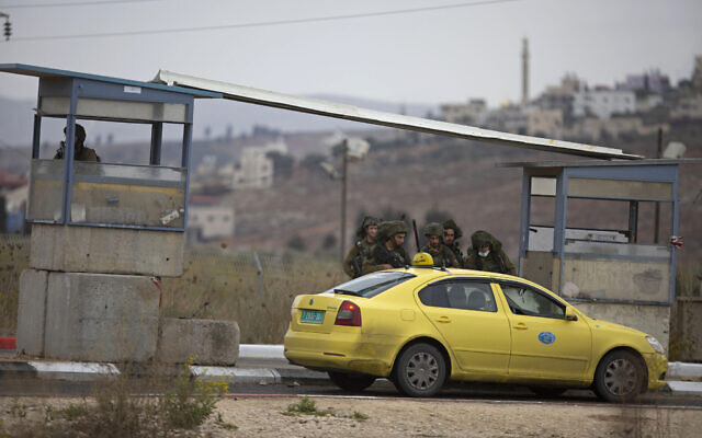 Illustrative: Israeli soldiers check a Palestinian taxi after a Palestinian gunman opened fire at a military post and troops returned fire, at the Huwara checkpoint south of the West Bank city of Nablus, November 4, 2020. (AP Photo/Majdi Mohammed) Illustrative: Israeli soldiers check a Palestinian taxi after a Palestinian gunman opened fire at a military post and troops returned fire, at the Huwara checkpoint south of the West Bank city of Nablus, November 4, 2020. (AP Photo/Majdi Mohammed)
