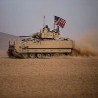 Illustrative: American soldiers drive a Bradley fighting vehicle during a joint exercise with Syrian Democratic Forces at the countryside of Deir Ezzor in northeastern Syria, December 8, 2021. (Baderkhan Ahmad/AP)