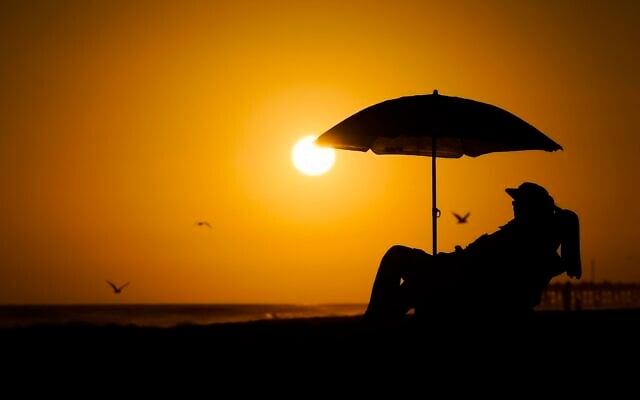FILE - A person rests under an umbrella as the sun sets, September 12, 2023, in Newport Beach, California. (AP Photo/Ryan Sun, File) FILE - A person rests under an umbrella as the sun sets, September 12, 2023, in Newport Beach, California. (AP Photo/Ryan Sun, File)
