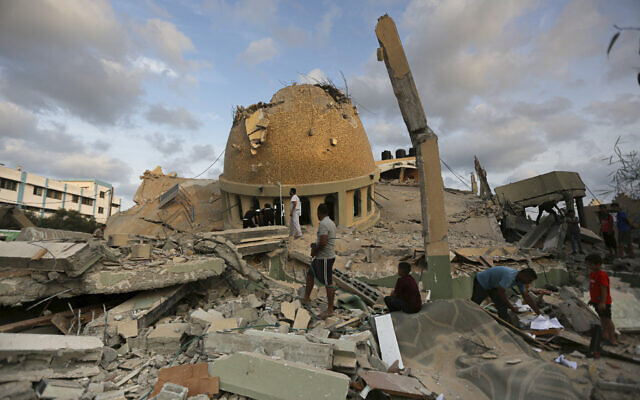 People stand outside a mosque destroyed in an Israeli airstrike in Khan Younis, Gaza Strip, October 8, 2023. (AP Photo/Yousef Masoud)