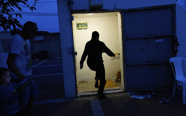 Illustrative: Israelis run to take cover in a shelter as a siren sounds a warning of incoming rockets fired from the Gaza strip, in Ashkelon, Oct. 8, 2023 (AP Photo/Ohad Zwigenberg) Illustrative: Israelis run to take cover in a shelter as a siren sounds a warning of incoming rockets fired from the Gaza strip, in Ashkelon, Oct. 8, 2023 (AP Photo/Ohad Zwigenberg)