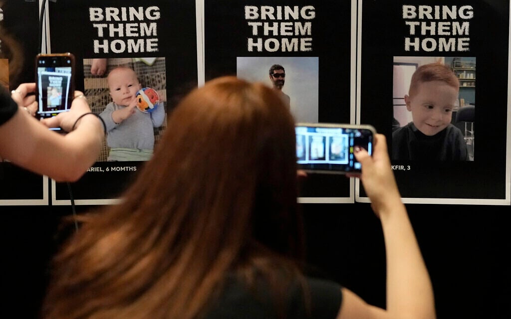 Journalists photograph missing persons posters ahead of a press conference of British children of Israeli hostages at a hotel in London, October 12, 2023. (AP/Kirsty Wigglesworth) Journalists photograph missing persons posters ahead of a press conference of British children of Israeli hostages at a hotel in London, October 12, 2023. (AP/Kirsty Wigglesworth)