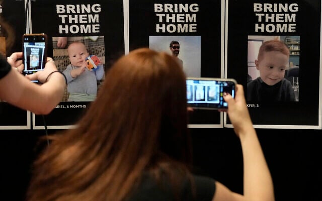 Journalists photograph missing persons posters ahead of a press conference of British children of Israeli hostages at a hotel in London, October 12, 2023. (AP/Kirsty Wigglesworth)