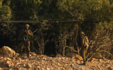Israeli soldiers take positions alongside the border wall and fence with Lebanon as seen from the Lebanese side of the Lebanese-Israeli border in the southern village of Marwaheen, Lebanon, October 12, 2023. (AP Photo/Hassan Ammar)