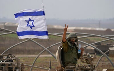 An Israeli soldier flashes a V-sign from an armoured personnel carrier (APC) as they head towards the Gaza Strip border in southern Israel, Oct. 14, 2023. (AP Photo/Ariel Schalit)