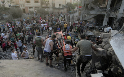 Palestinians evacuate a survivor from a destroyed house hit by an Israeli airstrike in town of Khan Younis, southern Gaza Strip, during the Israel-Gaza war, October 17, 2023. (AP Photo/Mohammed Dahman)