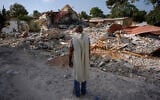 Illustrative: An Israeli man wearing a prayer shawl prays next to houses destroyed by Hamas terrorists in Kibbutz Be'eri, October 22, 2023. (AP Photo/Ariel Schalit, File)