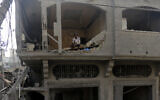 A Palestinian man watches as others inspect the damage to destroyed houses after Israeli airstrikes on Gaza City,  in the northern Gaza Strip, October 24, 2023. (Abed Khaled/AP)