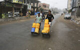 Palestinians push carts with water canisters in Rafah on Sunday, Oct. 29, 2023. (AP/Hatem Ali)