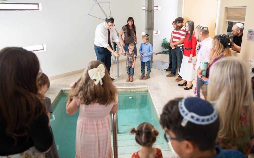 Or Tzion Rabbi Andy Green holds the hand of Jubal Most, 3, and he and his family and fellow congregants look on as the rabbi explains the mikveh ritual bath on August 17, 2023 at Congregation Beth Israel in Paradise Valley, Arizona. (Caitlin O’Hara).