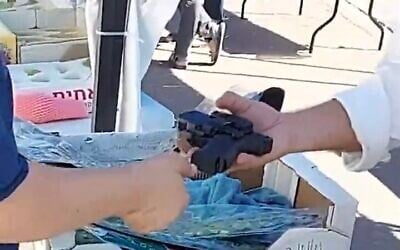 Screen capture from video of National Security Ministry chief of staff Chanamel Dorfman, left, handing his state-issued pistol to a man in the street, September 29, 2023. (X. Used in accordance with Clause 27a of the Copyright Law)