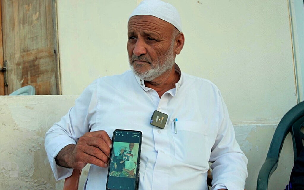 Ali Ziyadne showing an image on his phone of his brother Youssef and his nephews Bilal and Hamza, kidnapped by Hamas and taken hostage in Gaza on October 7, Rahat, October 30, 2023. (Eli Katzoff / Times of Israel)